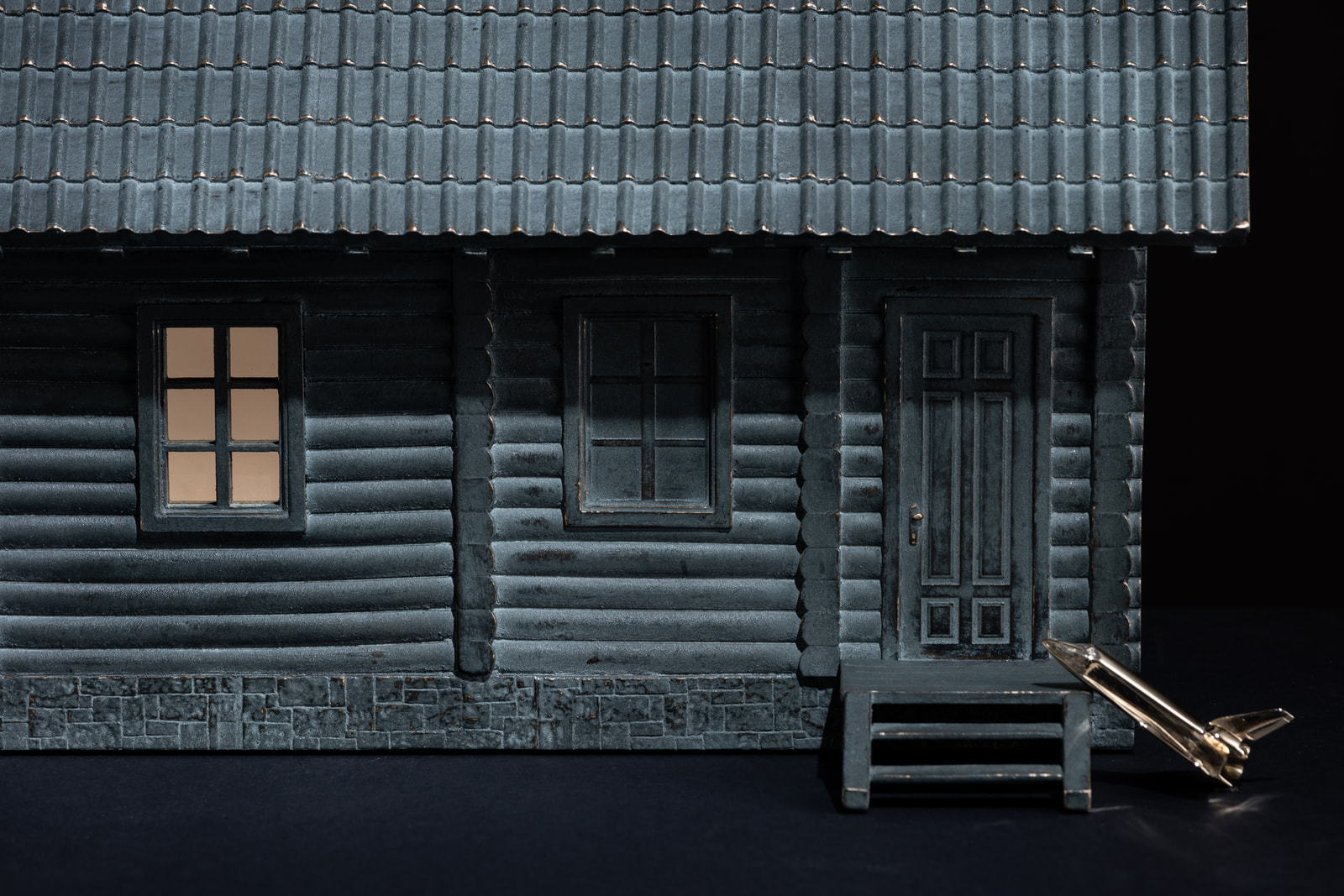Dim — the front of the house: lit window, door and porch steps with the shuttle