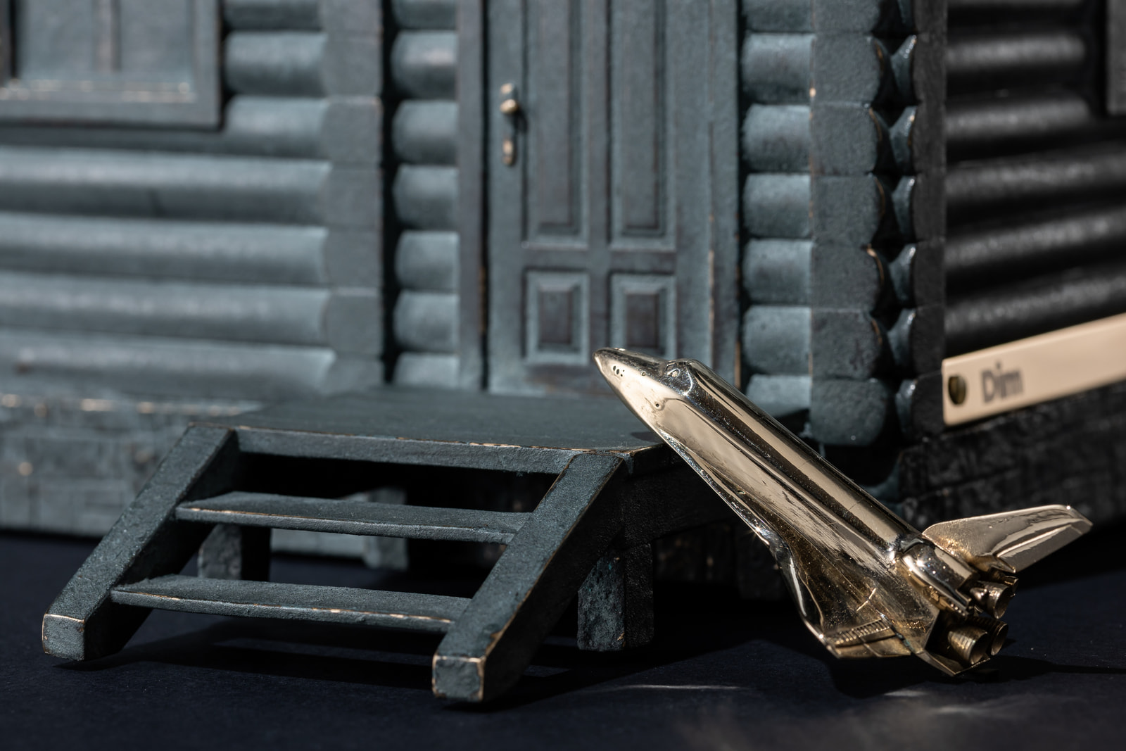 Dim — detail, the polished shuttle resting by the porch steps
